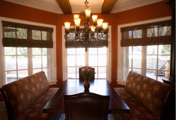 Woven wood blinds add natural elegance to a well-lit living room with large windows.